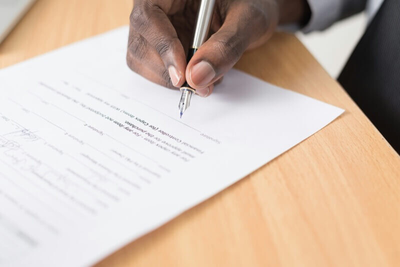 close up of hand signing a document.